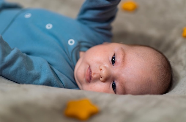 水色の服を着た生まれたばかりの男の子赤ちゃんは仰向けになって甘い顔をします