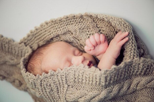 生まれたばかりの男の子はニットの毛布に包まれた生まれたばかりの男の子を編みました