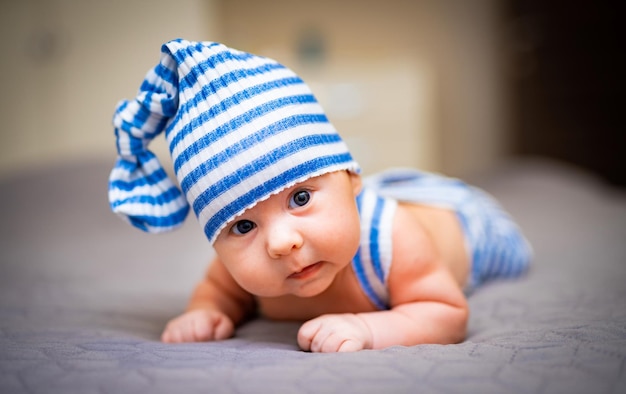 Newborn baby boy in light blue clothes baby lies on his stomach
and makes a sweet face