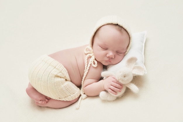 Neonato che dorme su sfondo bianco. medicina e concetto di salute, maternità e paternità felici. capretto in cappello e con il coniglietto. carta di pasqua. ospedale e clinica di maternità. festa del papà e della mamma