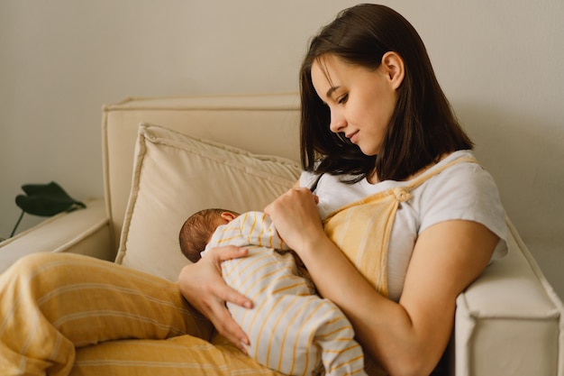 Newborn baby boy sucking milk from mothers breast. Portrait of mom and breastfeeding baby. Concept of healthy and natural baby breastfeeding nutrition.