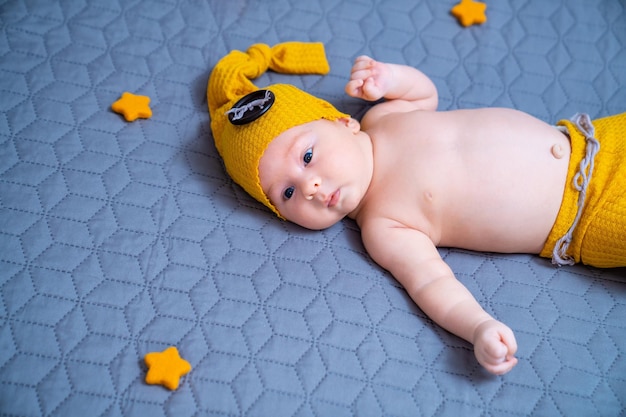 Newborn baby boy in suit on a grey background In a hat