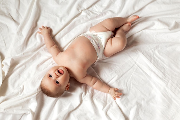 Newborn baby in a diaper is lying on his back on a white sheet. products for children, toy. concept of a happy childhood and motherhood. child care. space for text. High quality photo