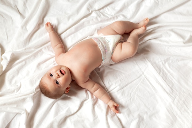 Newborn baby in a diaper is lying on his back on a white sheet products for children