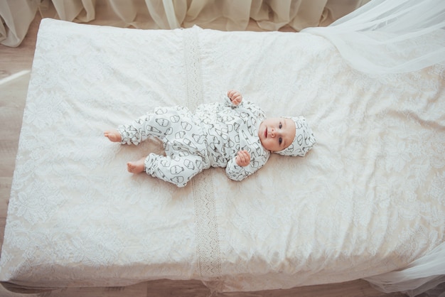 Newborn baby dressed in a suit on a soft bed. top view