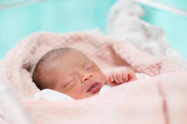 Newborn baby face closeup Sleeping on bed in hospital after birth