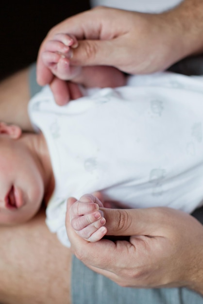 生まれたばかりの赤ちゃんと手をつなぐ父男は赤ちゃんの手を握る父愛の概念