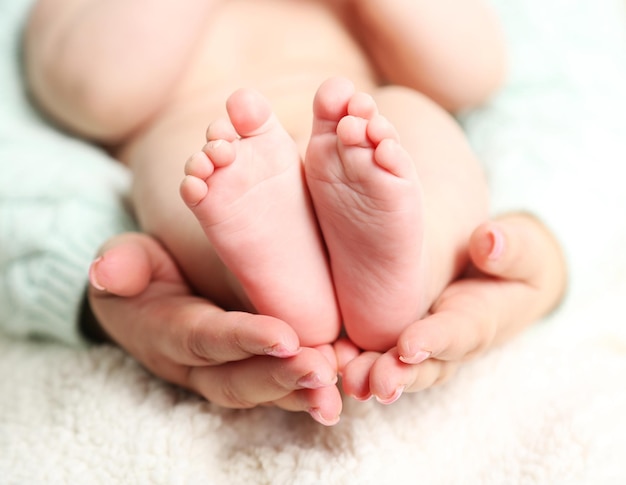 Newborn baby feet on female hands closeup