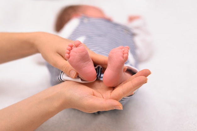 Foto piedi del neonato su mani femminili genitore che tiene in mano i piedi del neonato