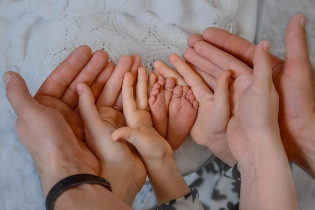 Foto i piedi del neonato e le mani dei genitori le palme insieme