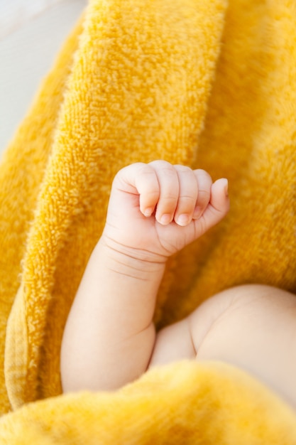 Photo newborn baby fist on yellow towel