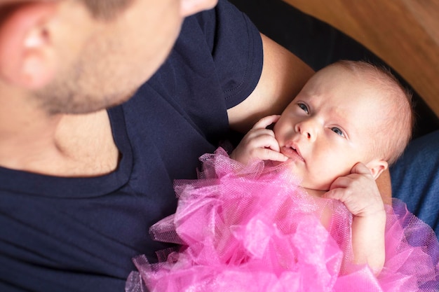 Newborn baby girl in the arms of her dad