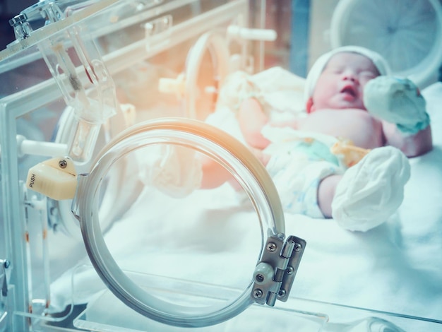 Newborn baby girl inside incubator in hospital post delivery room