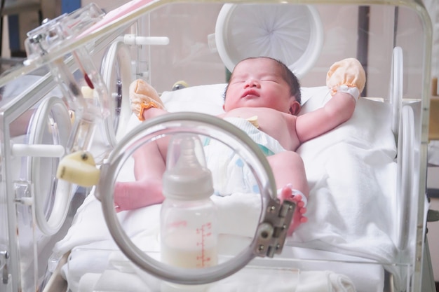 Newborn baby girl inside incubator in hospital post delivery room