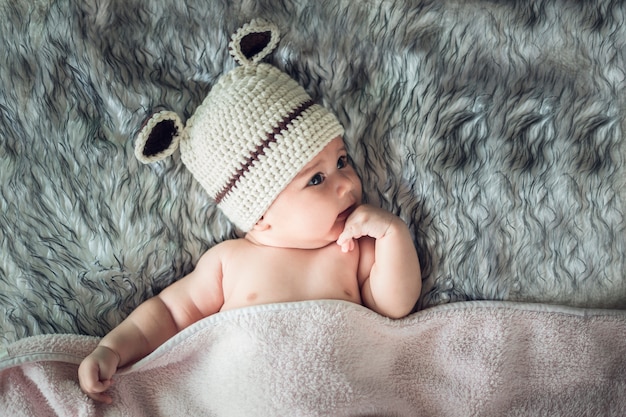 Newborn baby girl posed in a bowl on her back, on blanket of fur