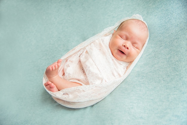 Newborn baby girl sleeping and yawning wrapped in a cocoon