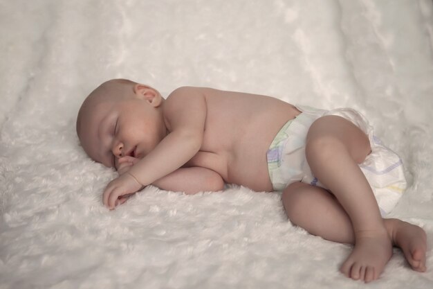 Newborn baby girl sleeps sweetly on light surface