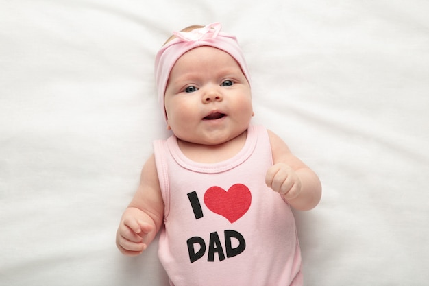 Photo newborn baby girl in t-shirt with inscription i love dad