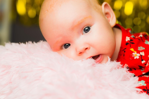 Newborn baby girl with blue eyes on a pink blanket