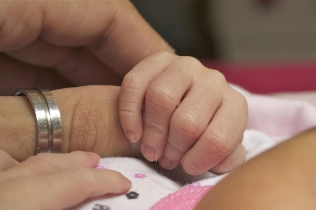 Newborn baby hand grasping a finger