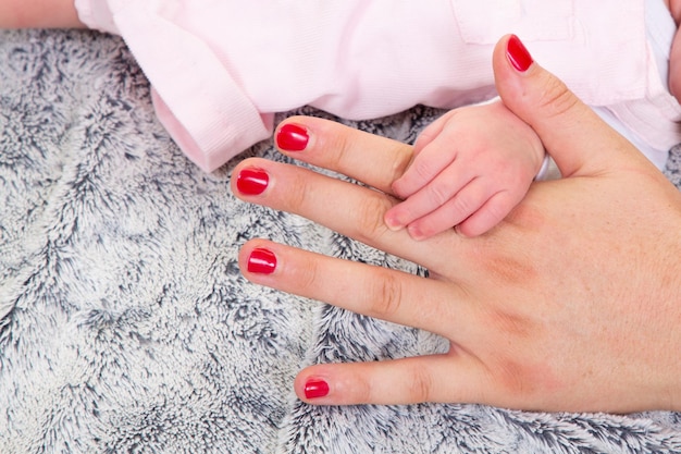 Newborn baby holding mother finger hand