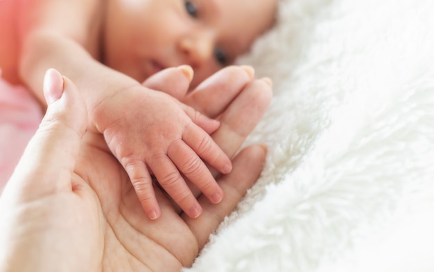 Newborn baby is holding mother's hand. selective focus. people.