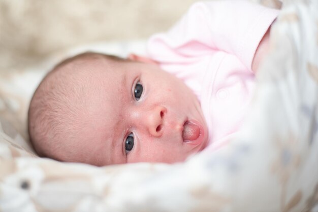 写真 新生児は横に横たわり口を開け舌を出して新生児の概念の皮膚