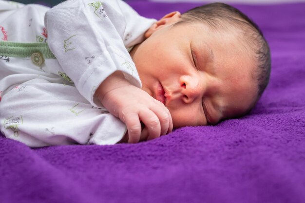 Newborn baby isolated sleeping in white cloth with purple background from different angle