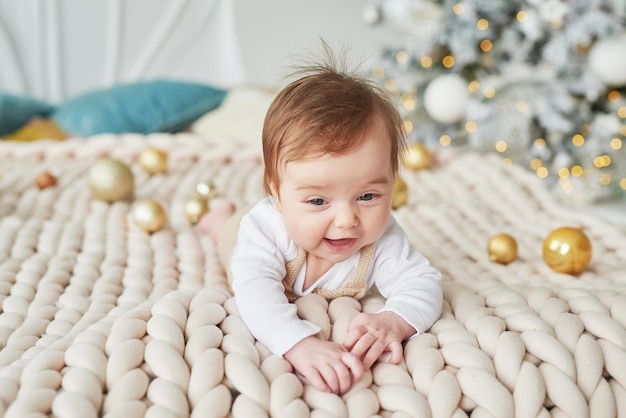 Newborn baby in knitted suit on background with Christmas balls