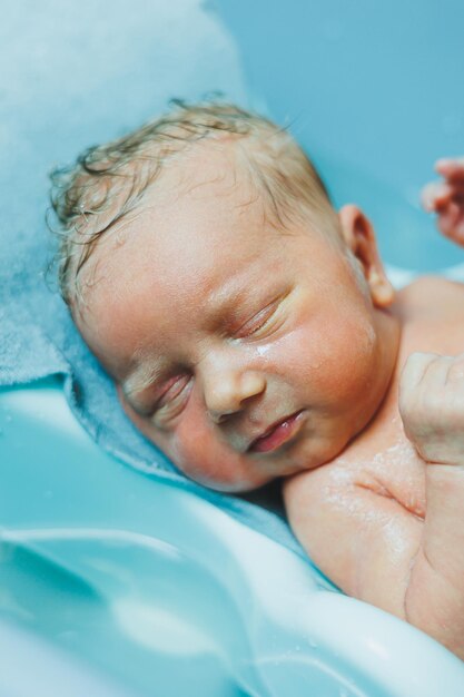 A newborn baby lies in a bathtub the first bathing of a newborn baby Bathing a newborn baby