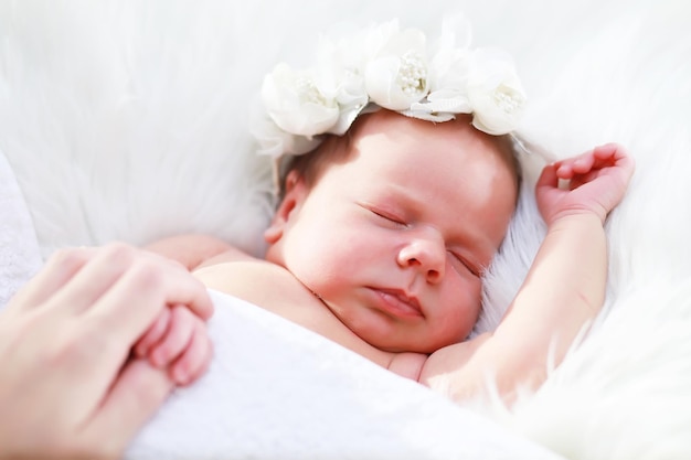 A newborn baby lies in her mother's arms A beautiful baby of European appearance is sleeping