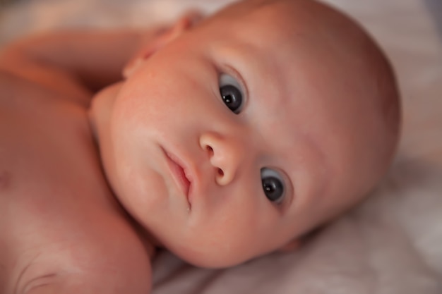 Newborn baby on light background shows its emotions