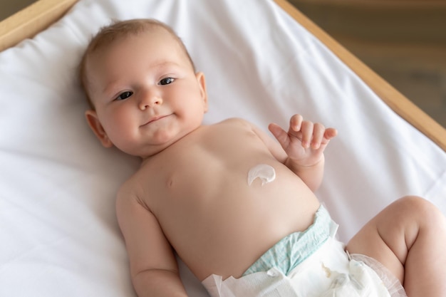 newborn baby lying on bed with cream on his tiny baby