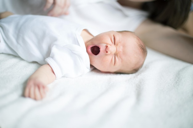 Newborn baby lying on the bed and yawns