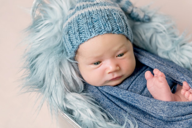 Newborn baby lying in trough with a blue blanket