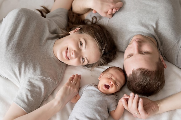 Newborn baby in mother's and father's arms on bed Postcard Mother's and father's day Children Protection Day World Happiness Day Smiling child Happy parenthood