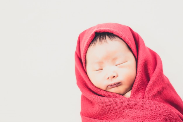 Newborn baby in red daiper sleeping on bed