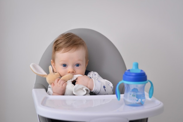 Photo newborn baby sitting on high chair with hand toy