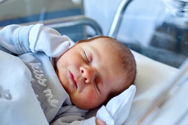 Newborn baby sleeping in its hospital crib