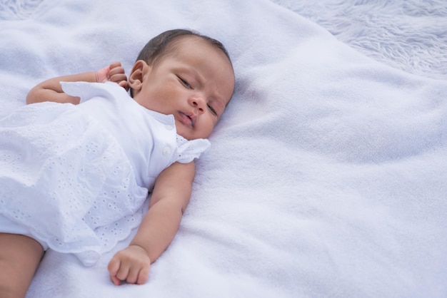 Newborn baby sleeping on white cushion with copy space