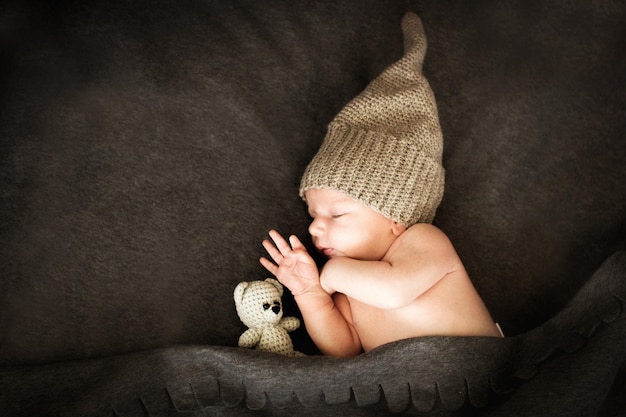 Newborn baby sleeping with a toy next to the knitted teddy bear