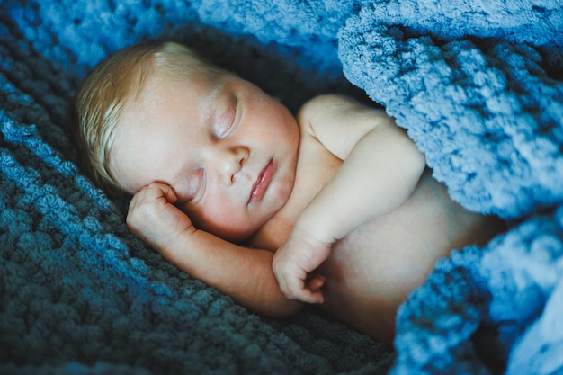 신생아 는 뜨개질 의 담요 에 잠을 자고 있다. 신생아 를 위한 자연 천 으로 만든 담요