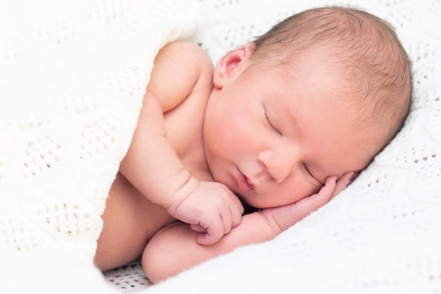 Newborn baby sleeps and smiles. close up portrait of beautiful sleeping baby