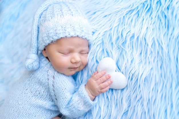 Newborn baby sleeps sweetly holding a heart toy in his hand, healthy baby sleep