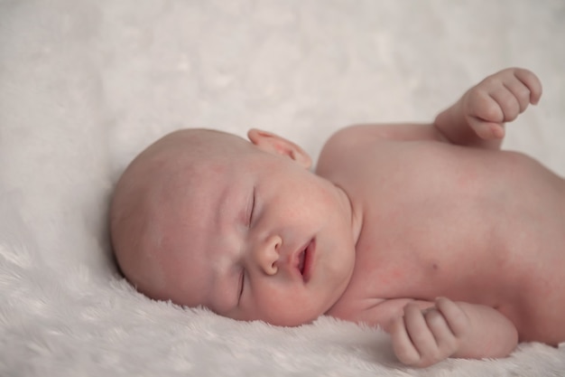 生まれたばかりの赤ちゃんは明るい背景で甘く眠ります