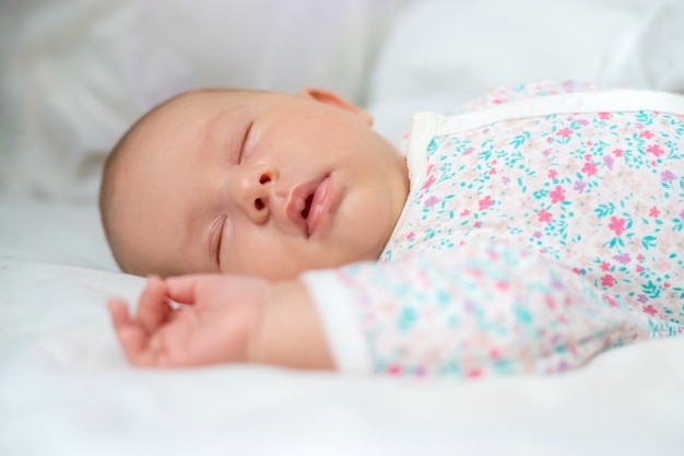 Newborn baby sleeps on a white bed