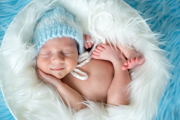 Newborn baby smiling in a dream on a blue background