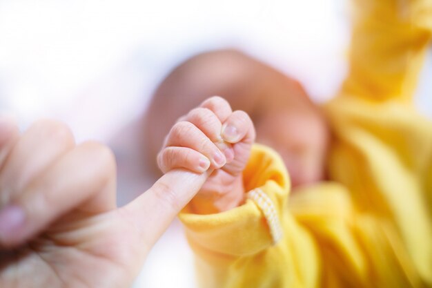 Newborn baby touching his mother hand