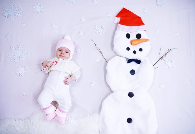 Newborn baby on a white background. Painting from white fabric. Snowman and baby. Christmas Holidays.