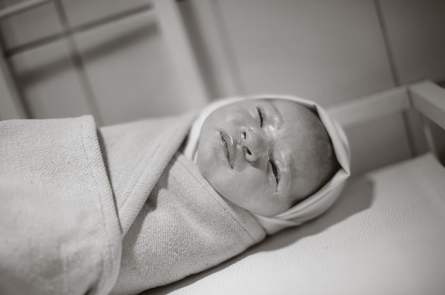 출생 후 싸인 신생아가 탁자 위에 놓여 있습니다. 흑백 사진입니다.